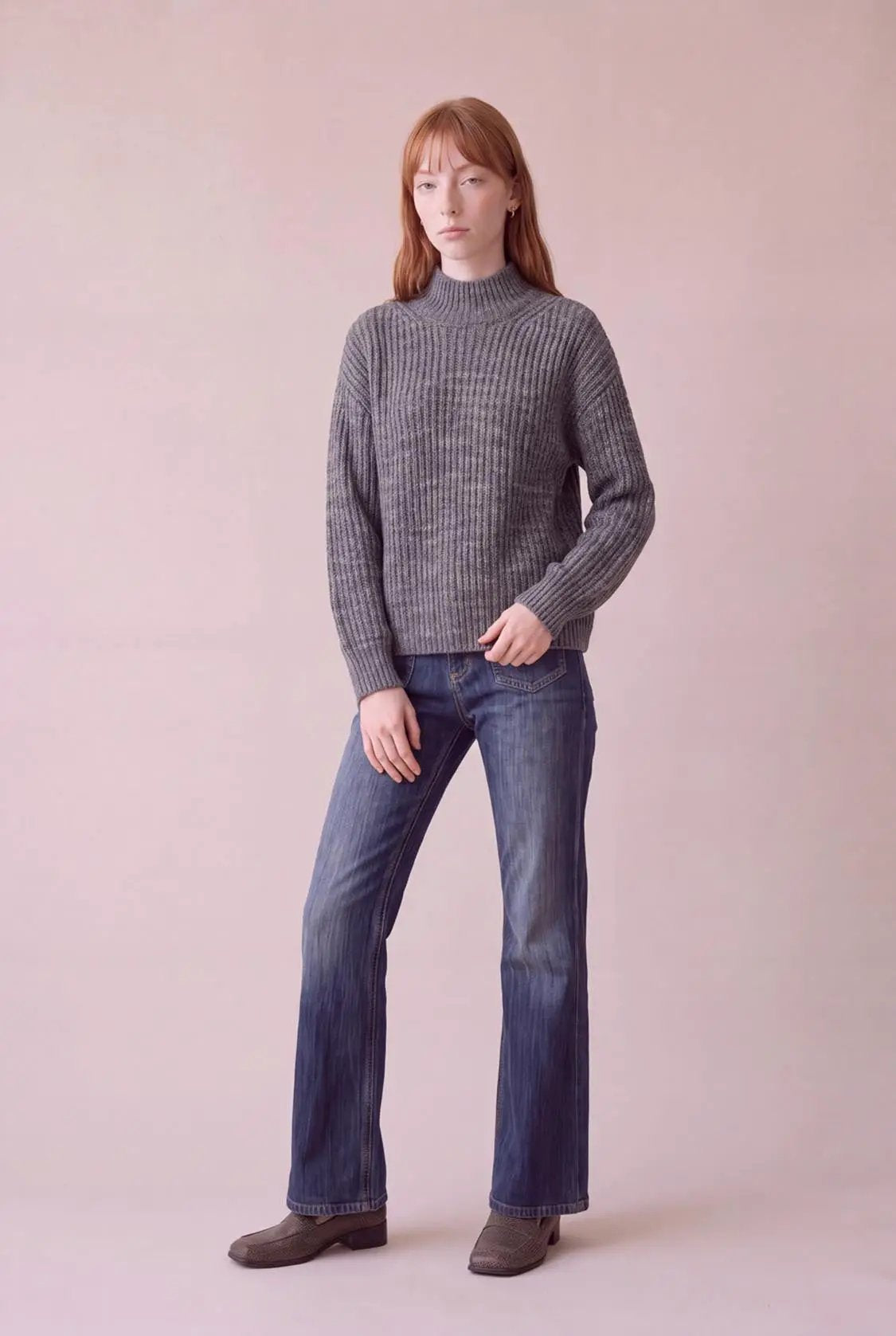 High-neck gray ribbed knit top with long sleeves worn by model in blue jeans