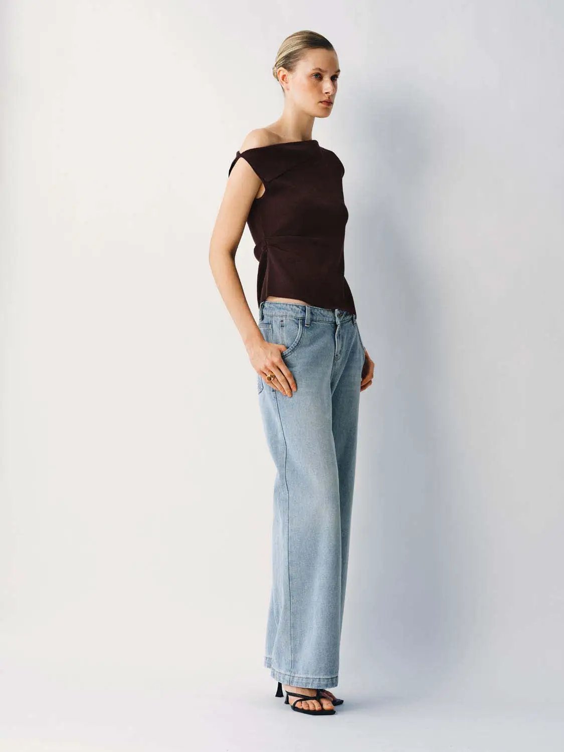 Medium Stretch T-Shirt dark brown knitted off-shoulder top on model with light denim jeans.