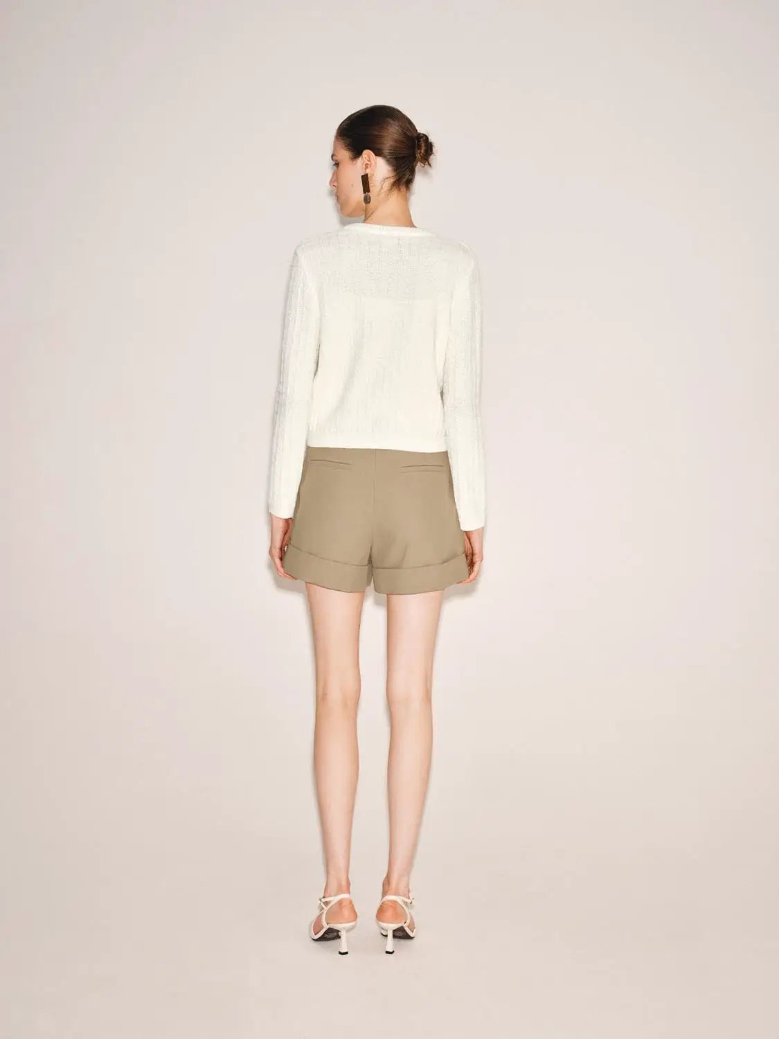 Knitted cardigan by Urban Revivo Fashion; white textured knit, back view with beige shorts.