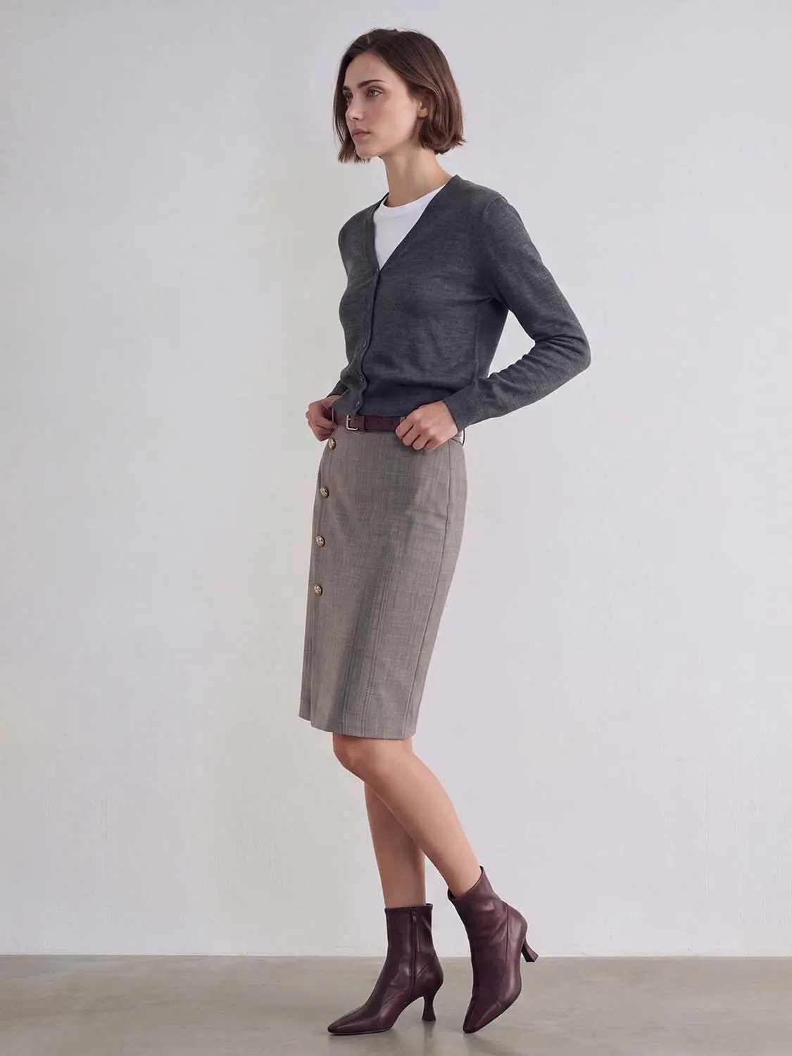 Knitted cardigan in dark gray worn with a white tee and plaid gray pencil skirt.
