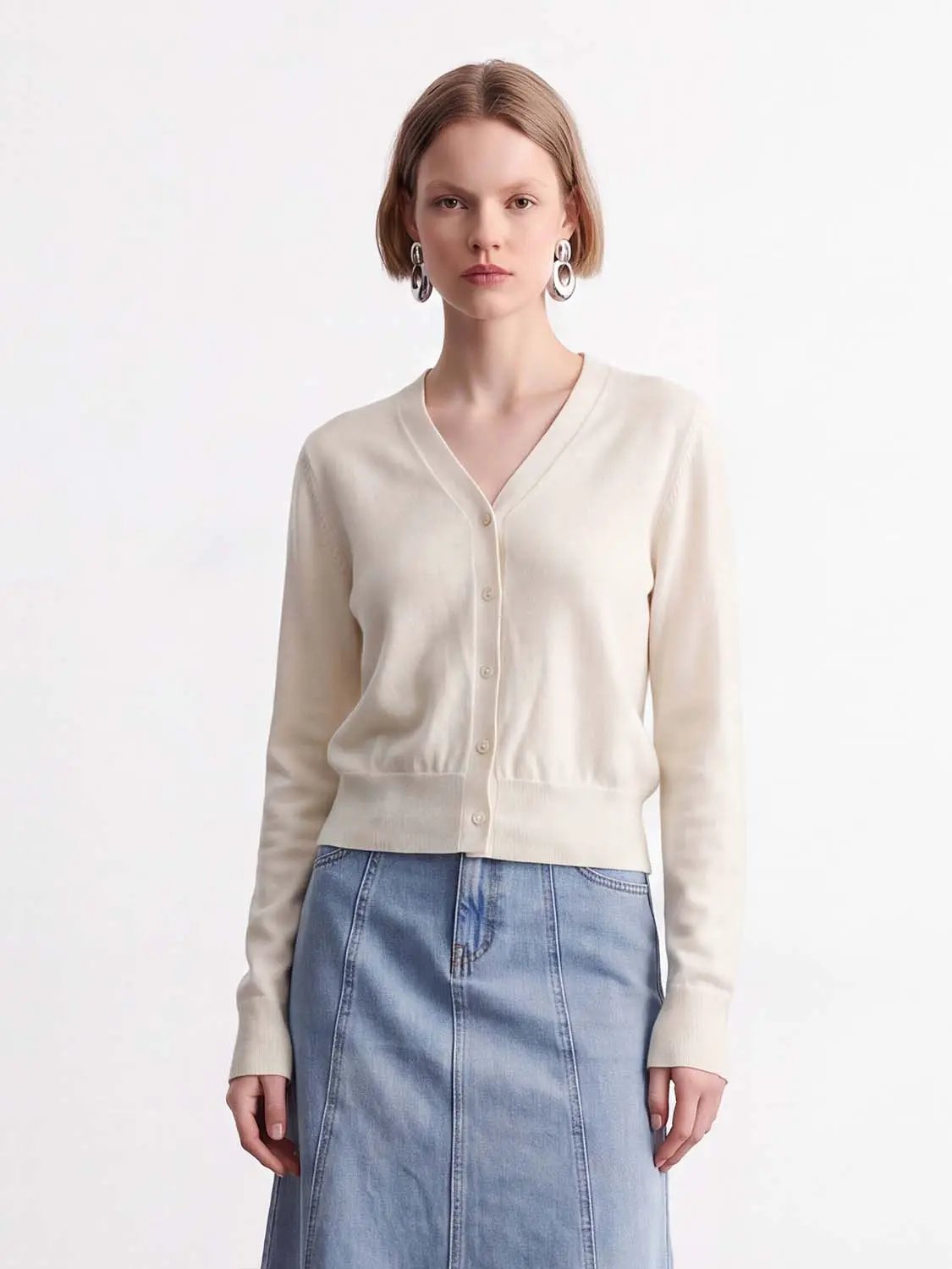 Knitted cardigan in cream with a V-neck, button-front closures and long sleeves.