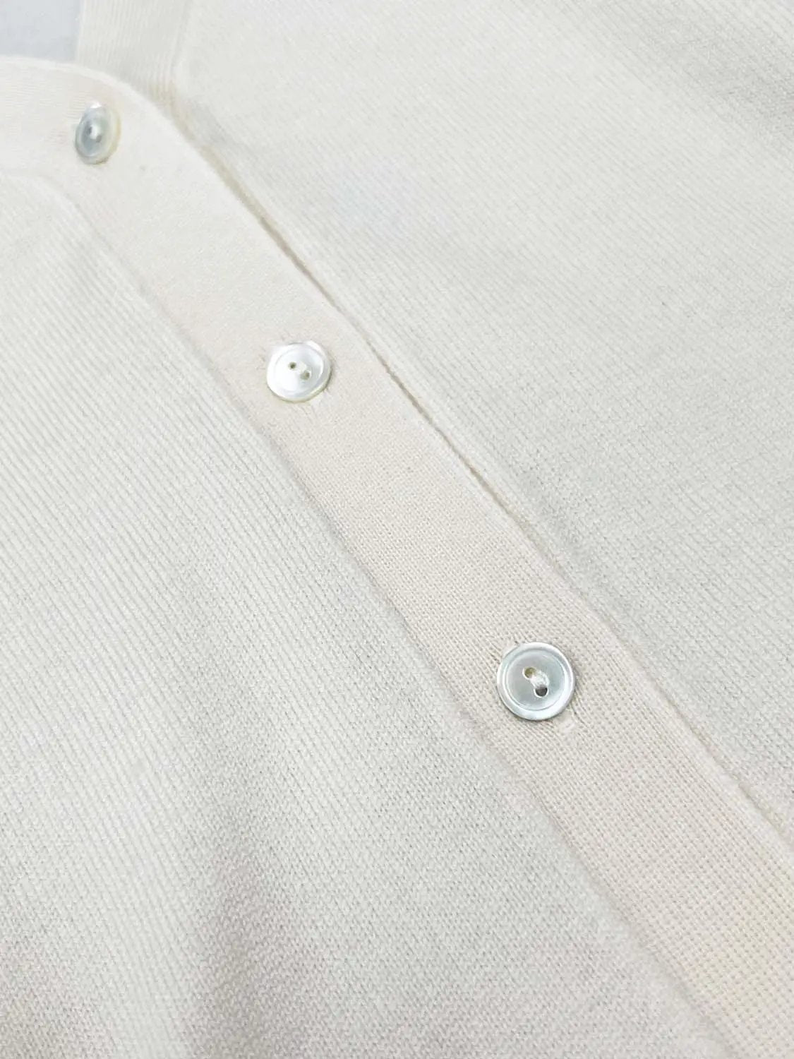 Knitted cardigan in cream with white buttons along the placket