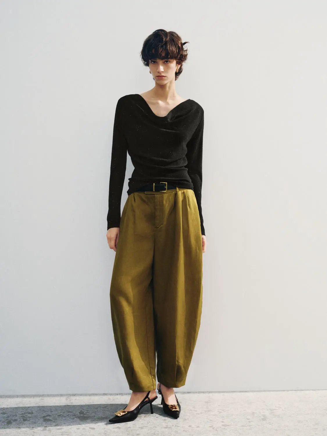 Knit T-Shirt, black knit top with a draped neckline, paired with mustard wide-leg pants on a model.