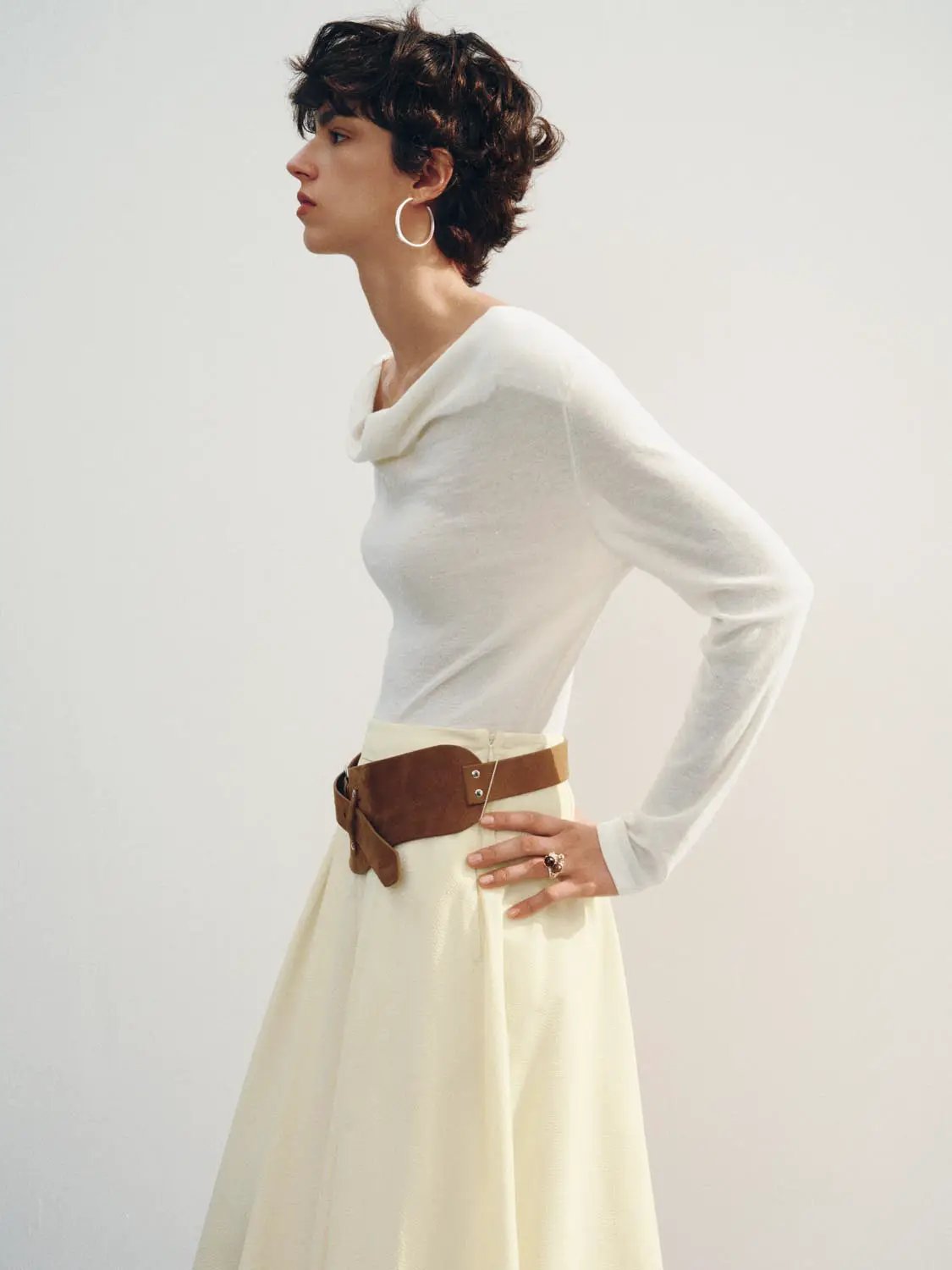 Knit T-Shirt in white with a cowl neck on a model, paired with a cream skirt and brown belt