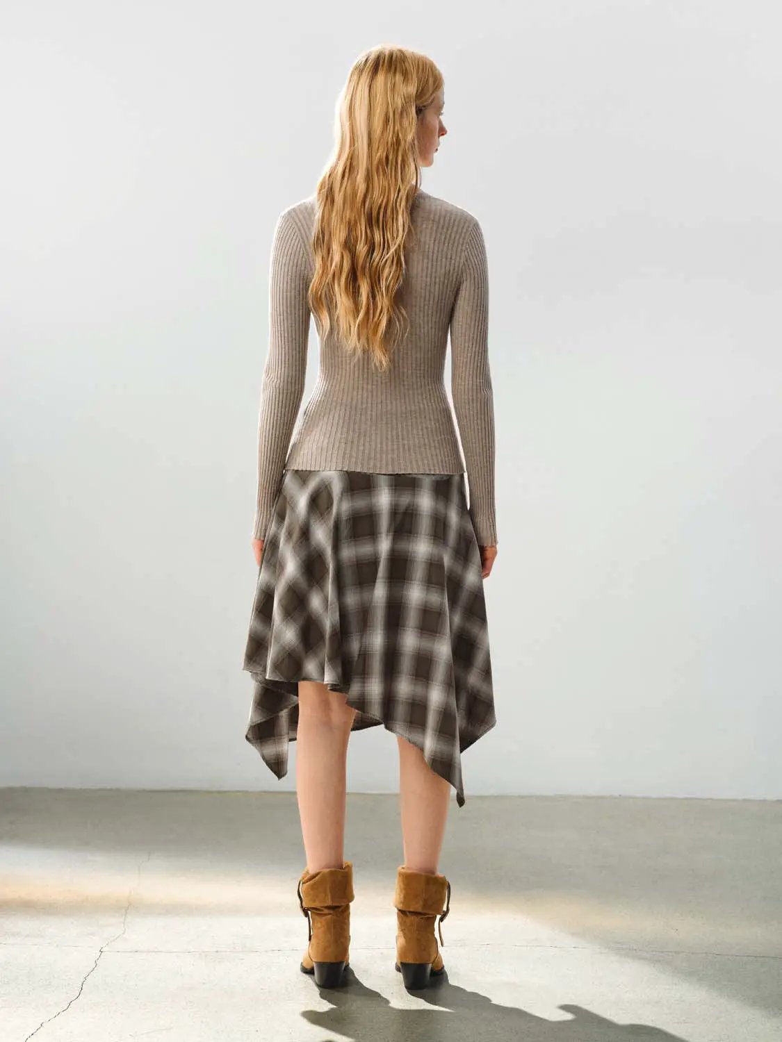 Fitted ribbed knit V-neck cardigan in taupe; long sleeves, paired with plaid skirt and brown boots.