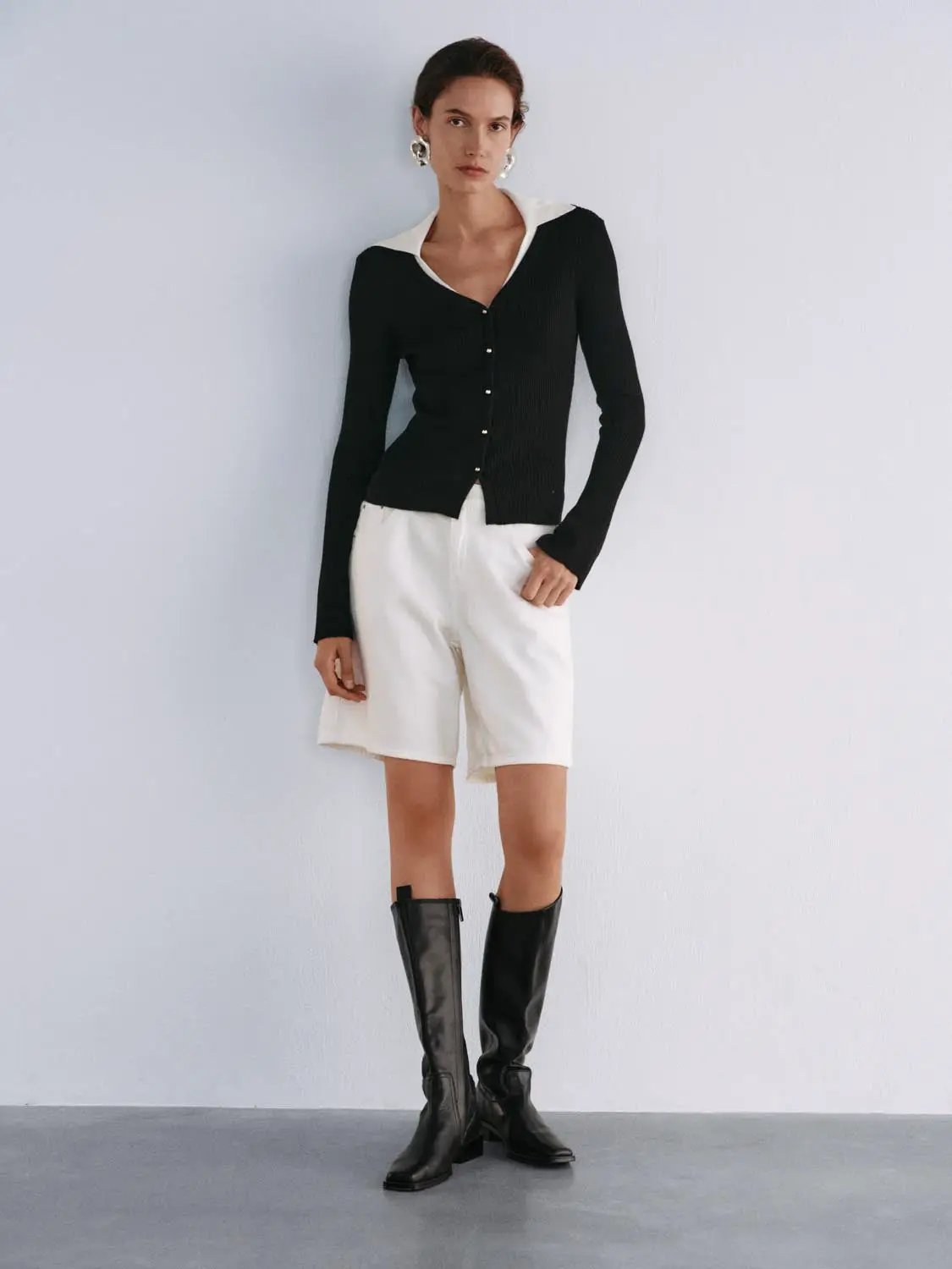 Knitted cardigan, black with white collar, button-down style.