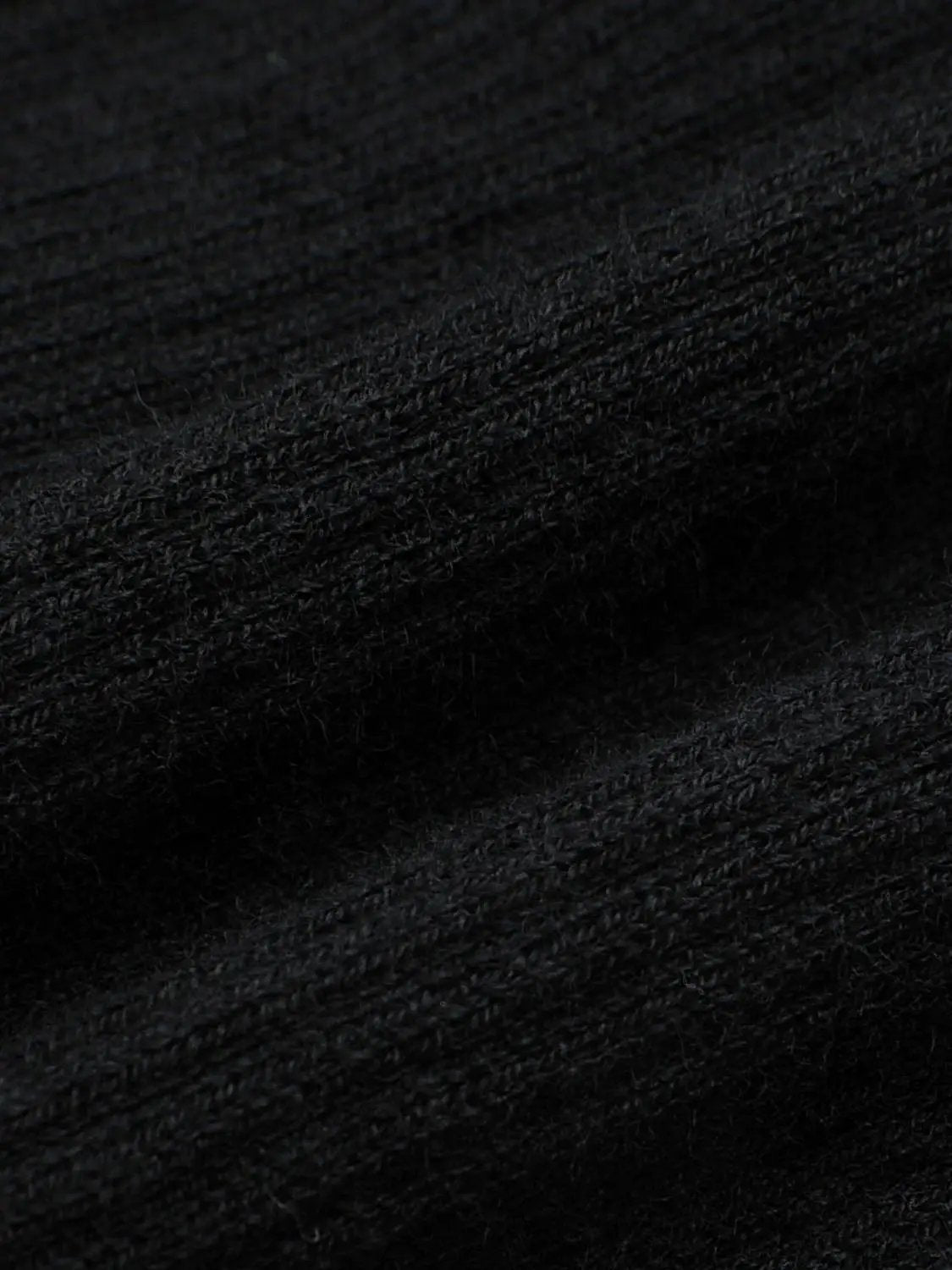 Knitted cardigan fabric in black with soft, fuzzy texture close-up