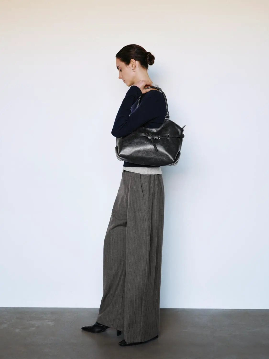 Fitted navy boat-neck long-sleeve knit top with contrast hem; paired with gray pinstripe wide-leg pants.