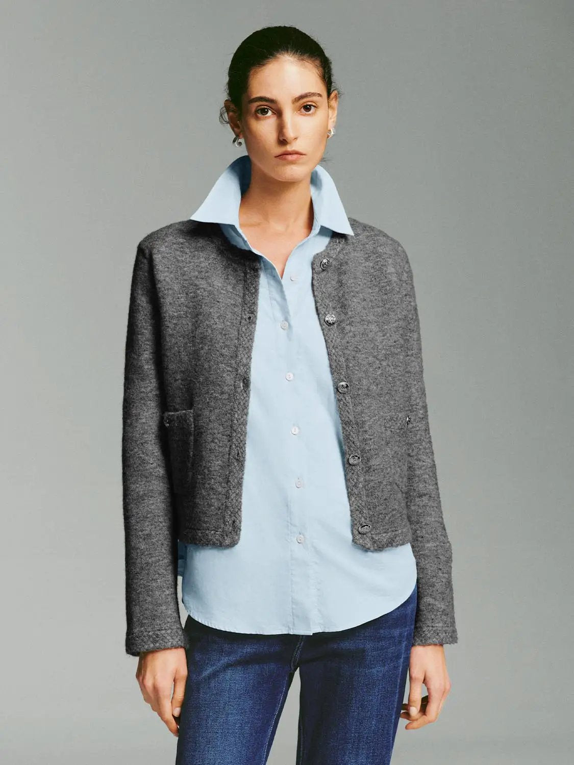 Crew-neck button-front long-sleeve knit cardigan in gray, worn over a light blue shirt.