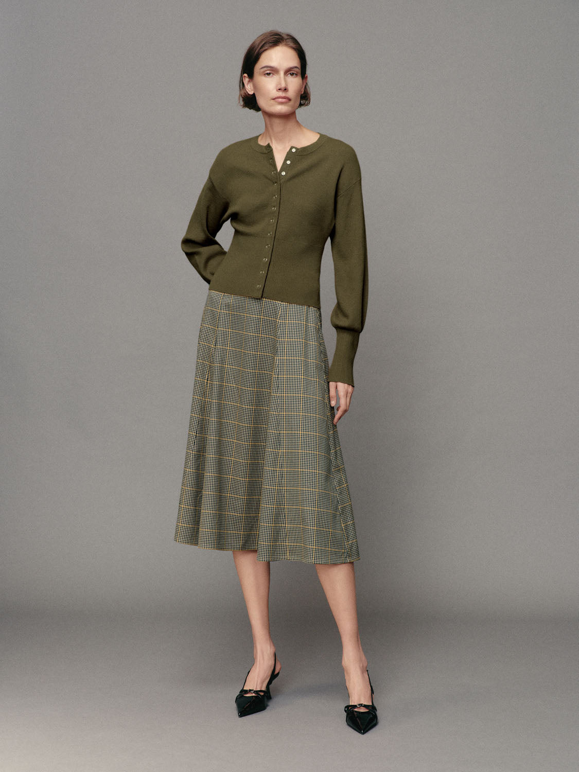Ribbed Button Front Crew Neck Long Sleeve Cardigan in olive green; paired with a plaid midi skirt for a polished look.