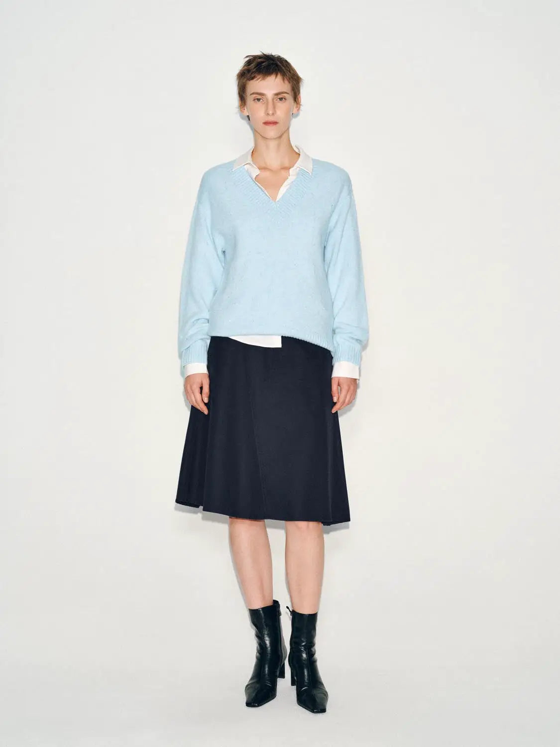 Knit T-Shirt in light blue knit, layered over white collared shirt with navy skirt.