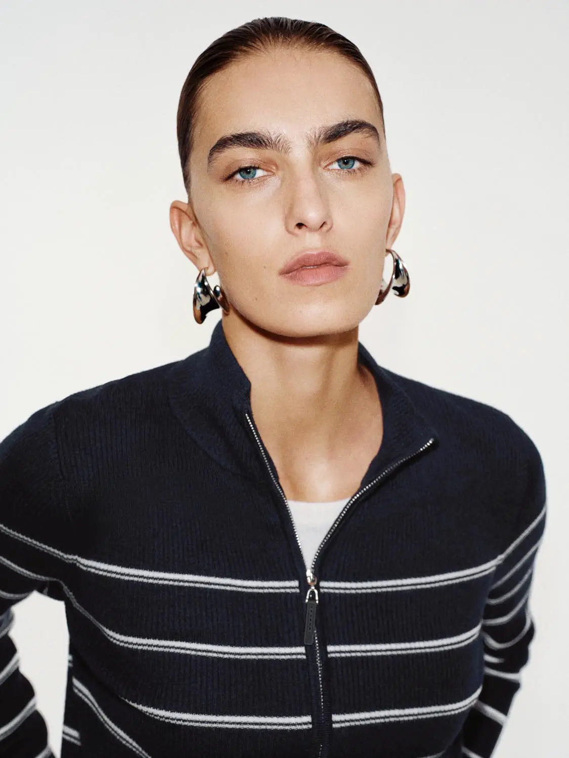 Knit jacket in navy with white horizontal stripes, zip-front, worn by model with silver hoop earrings.