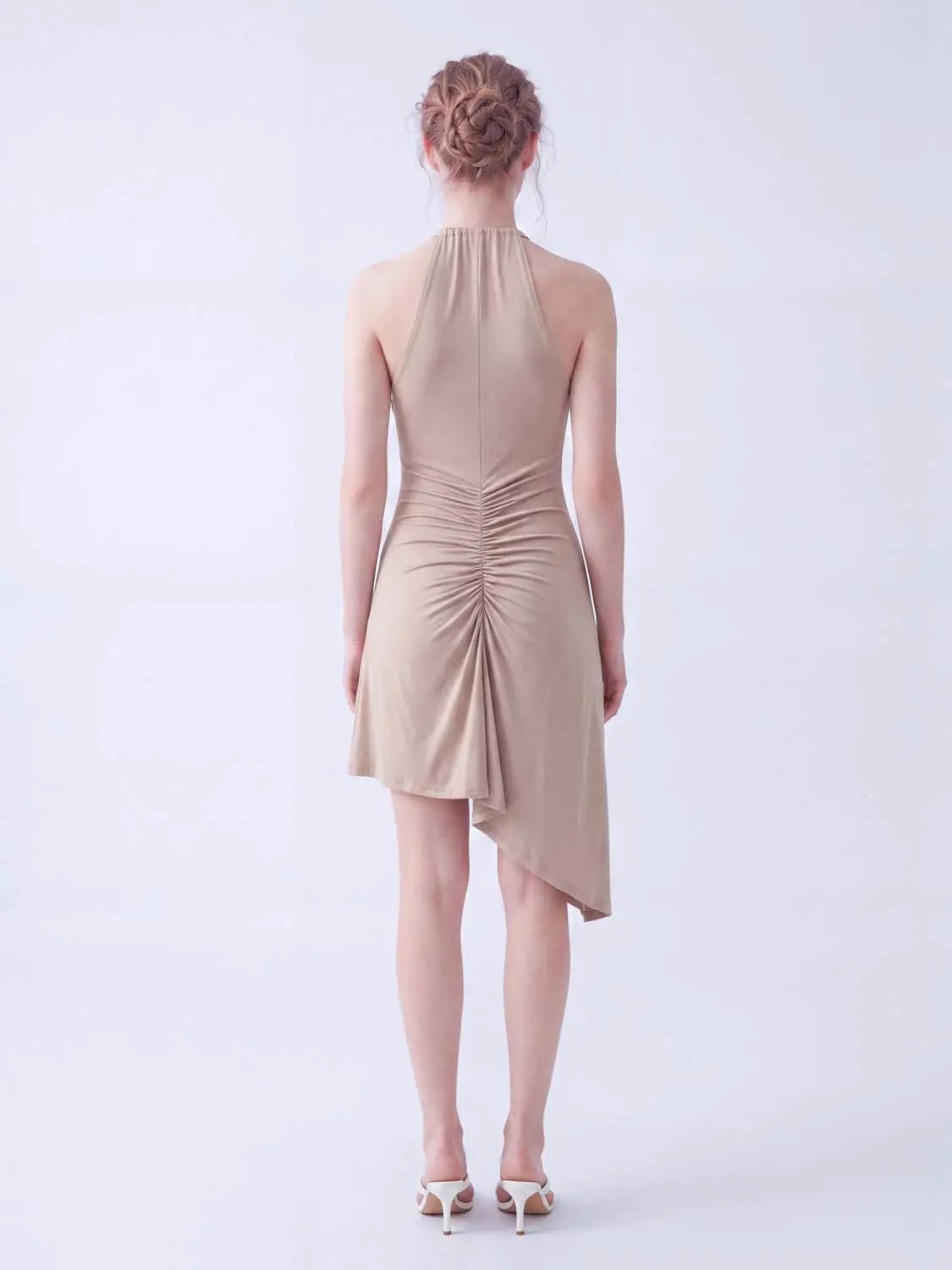 A-Line dress in beige satin with halter neck, back ruching, and an asymmetric hem.