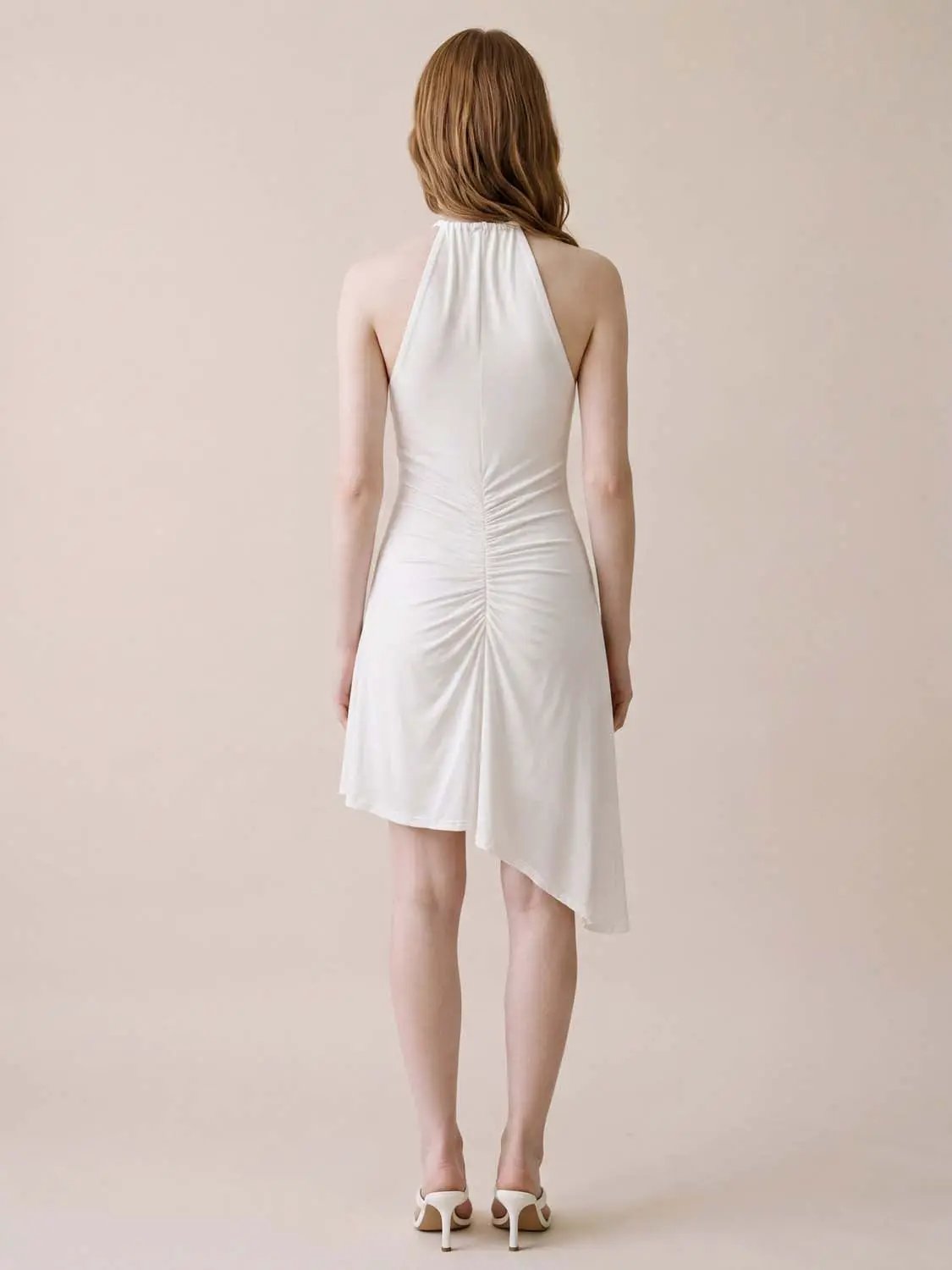 A-line dress in white with halter neckline, ruched back seam, and asymmetric hem