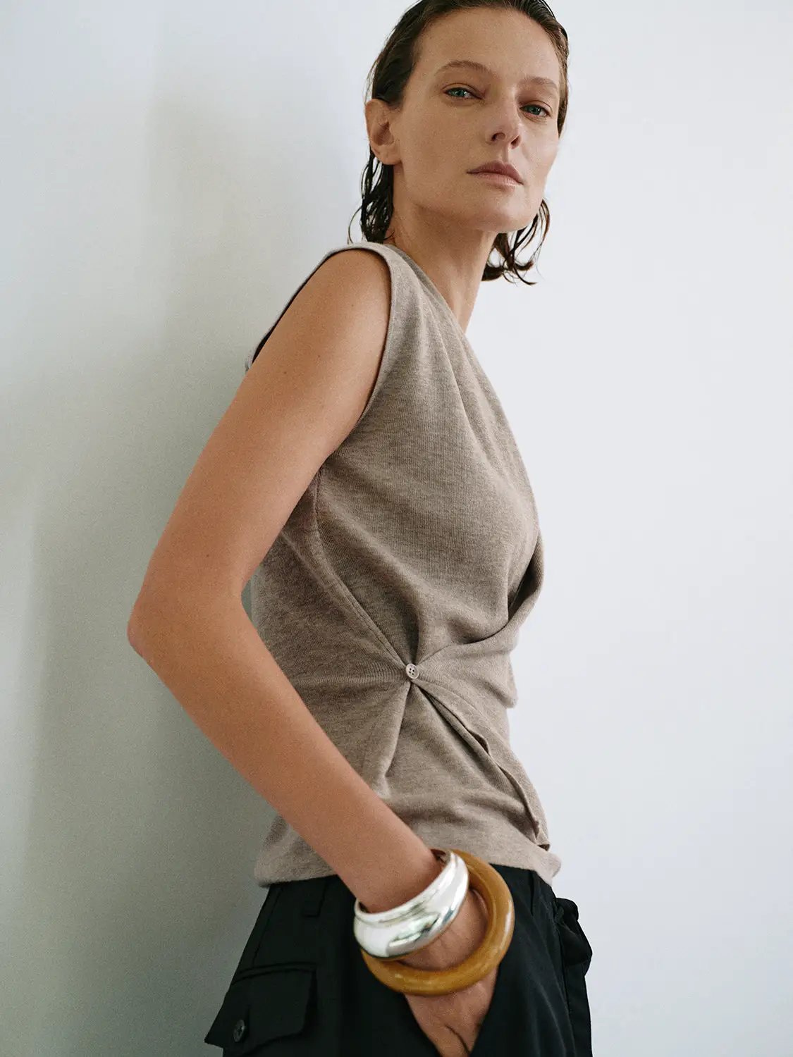Sleeveless knit wrap-front top with collar in taupe; model wearing with side knot detail.