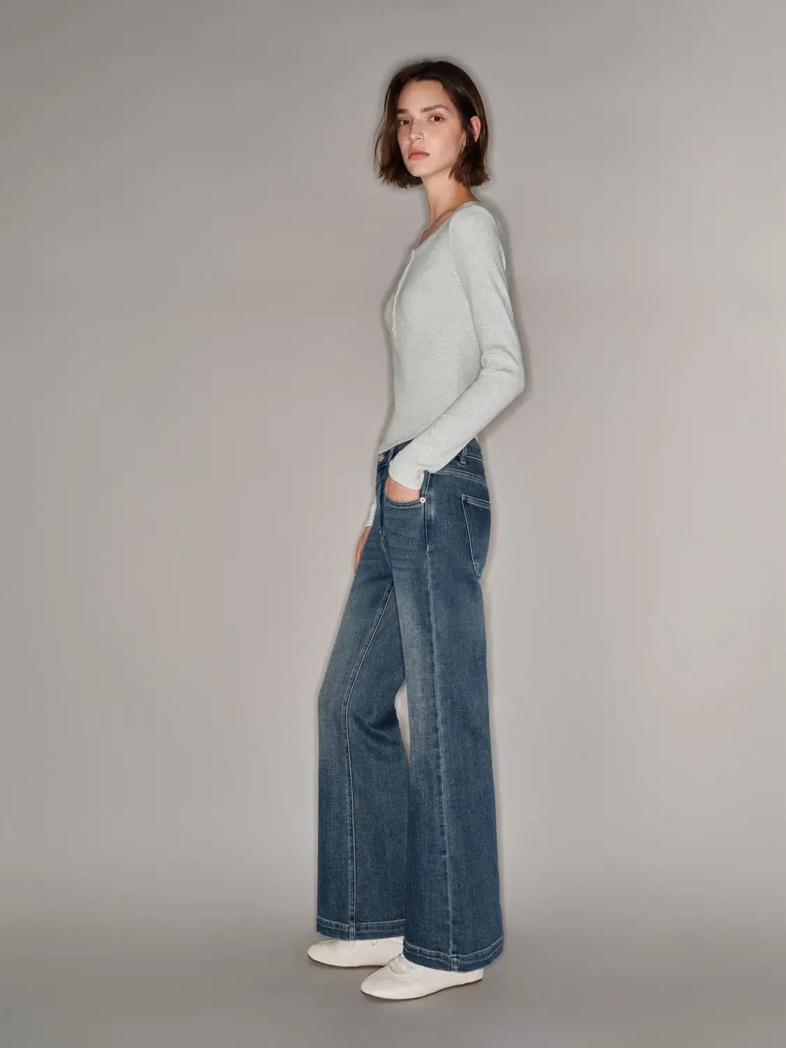 T-shirt with light gray color paired with blue wide-leg jeans and white sneakers on model.