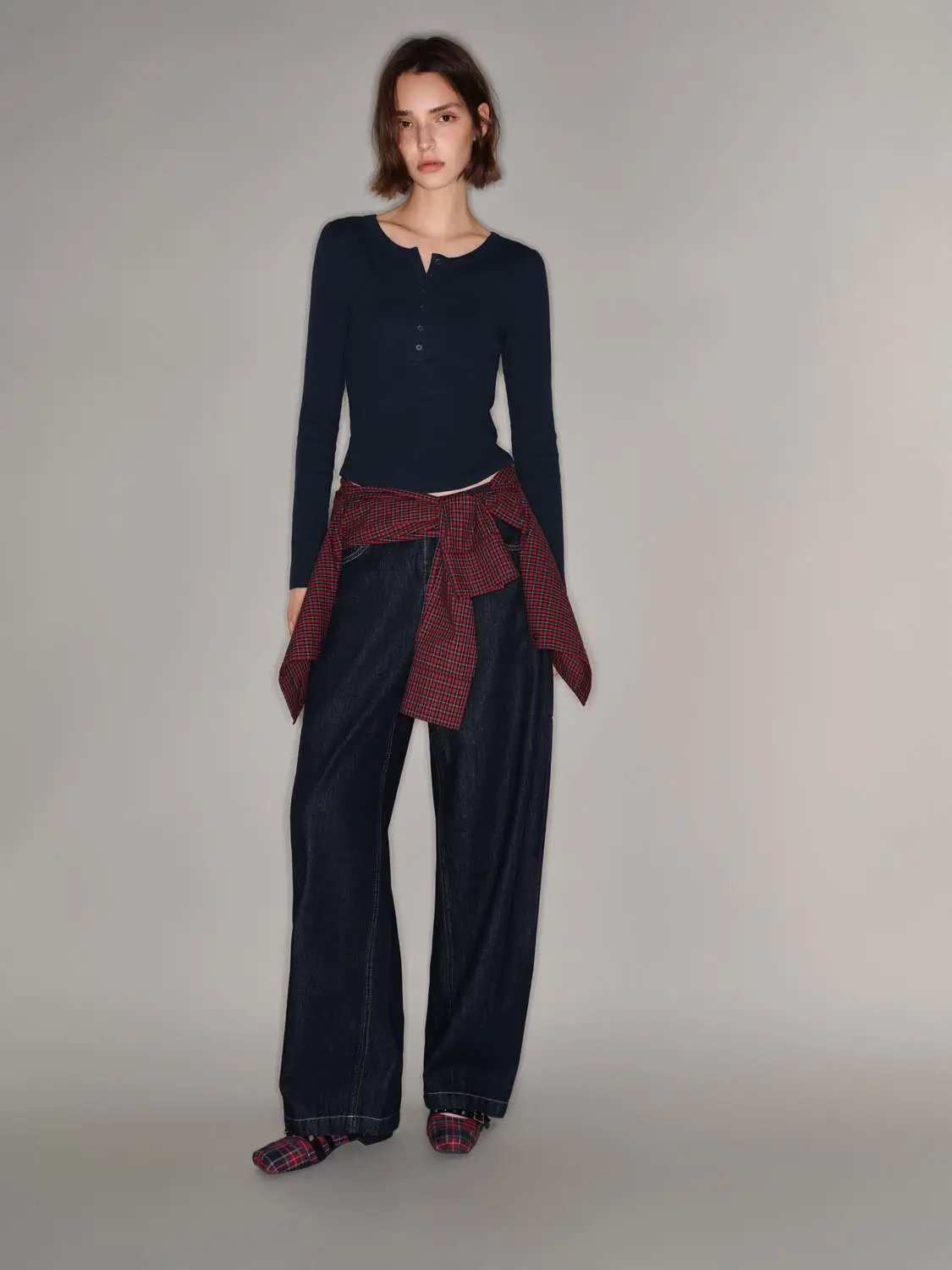 T-shirt by Urban Revivo, navy long-sleeve knit on a model with dark denim and a red plaid shirt tied at the waist