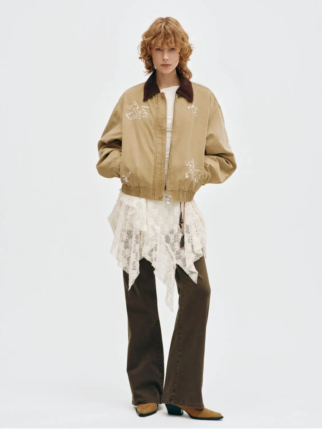 Padded jacket in beige with a brown corduroy collar and white embroidered motifs on the front, worn by a model.