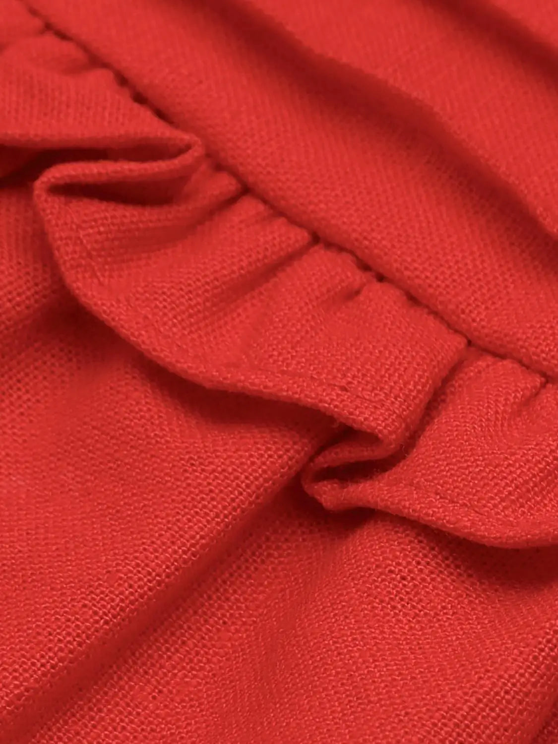 Red knit camisole top with folded strap detail and visible stitching.