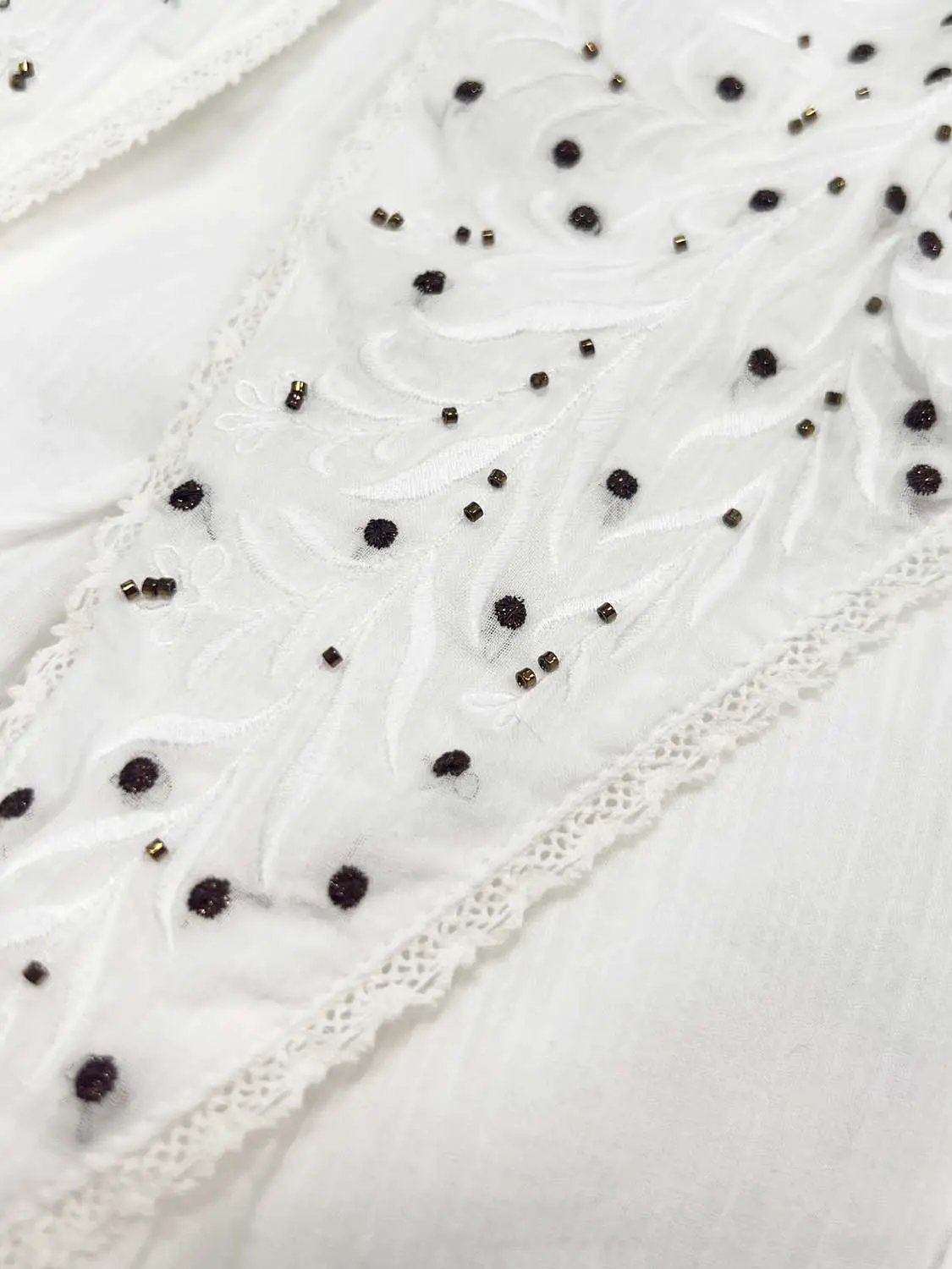 A-Line dress fabric close-up with white lace embroidery and black bead accents