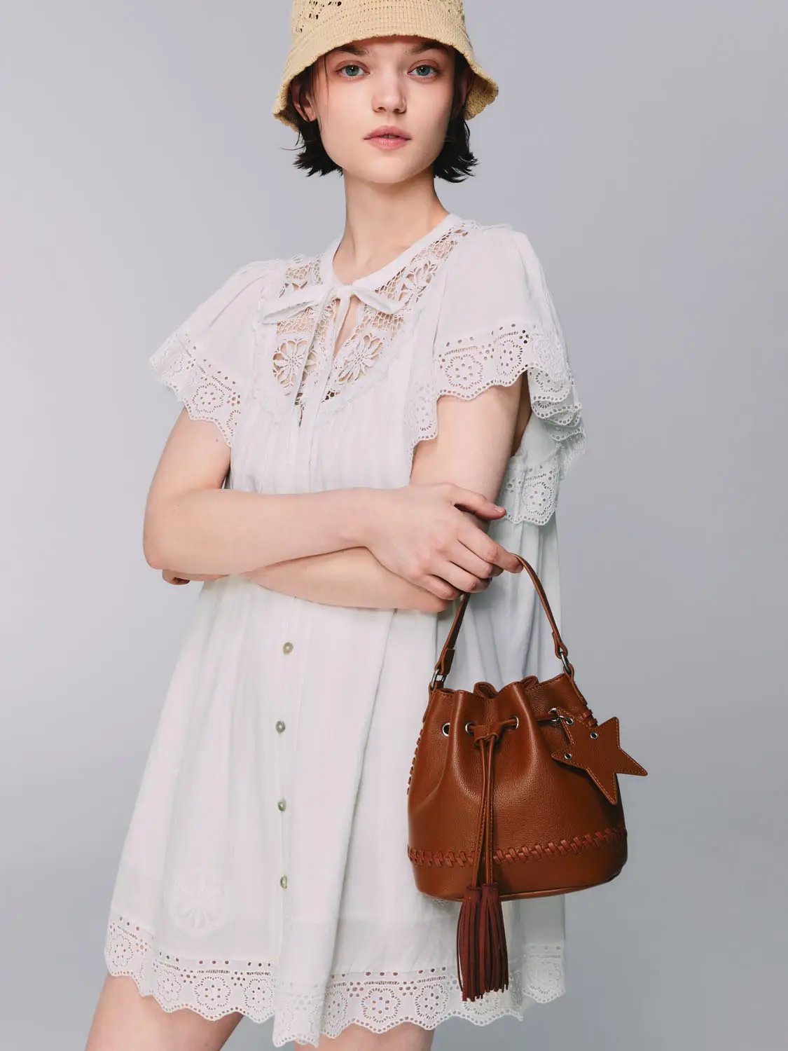 White cotton lace-collar dress with scalloped hem and lightweight lining, short flutter sleeves, shown with brown bucket bag