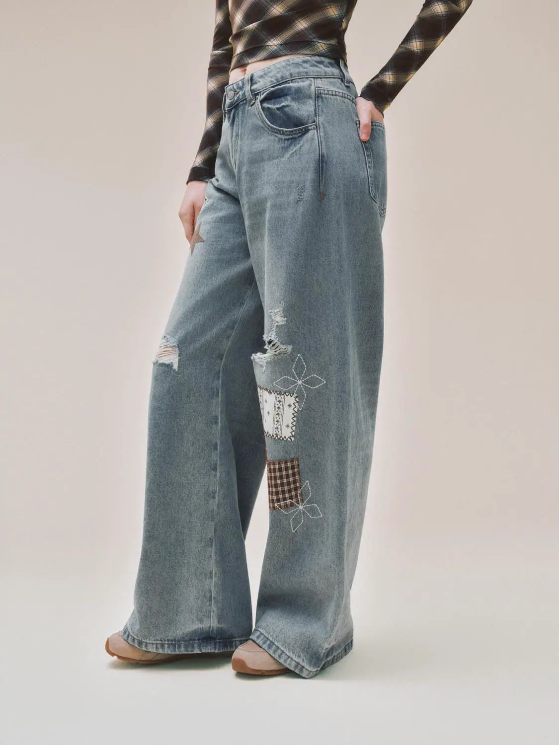 Patchwork ripped wide-leg low-rise cotton jeans; light blue denim with embroidered patches and distressed knees.