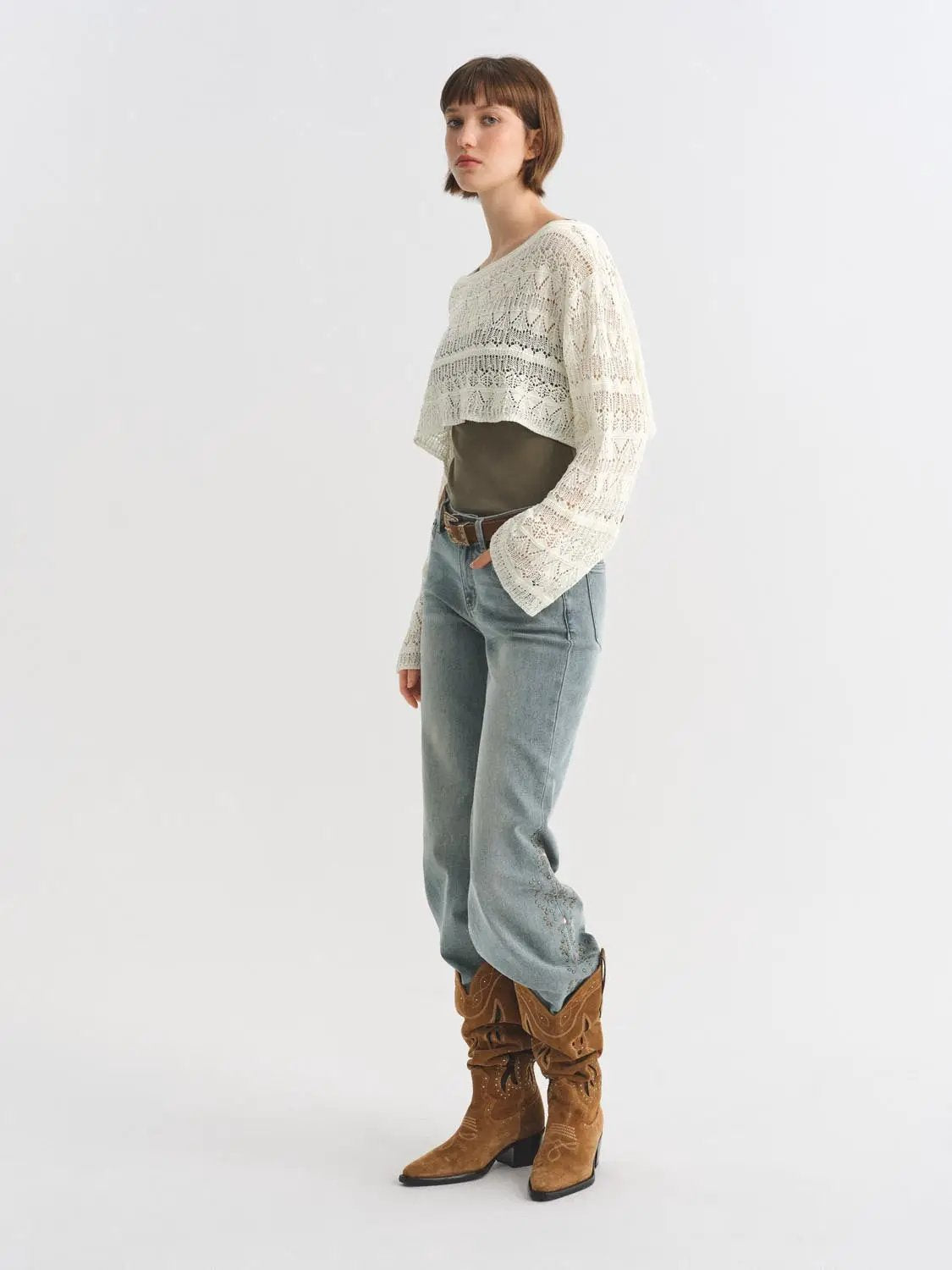 Jeans in light blue denim with a relaxed straight leg, paired with a brown belt and boots.