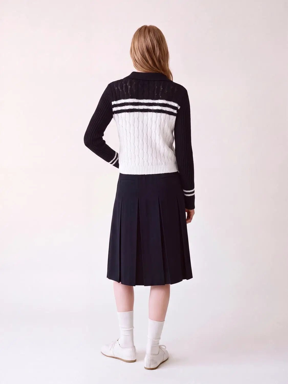 Striped collared knitted cardigan in black and white with cable-knit body and black sleeves.