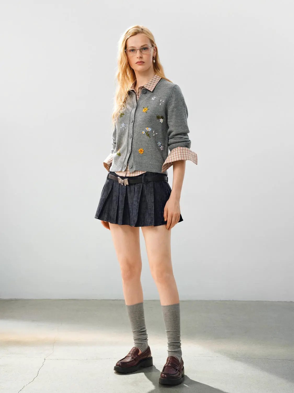 Knitted cardigan in gray with floral embroidery; three-piece outfit with a plaid shirt and pleated skirt.