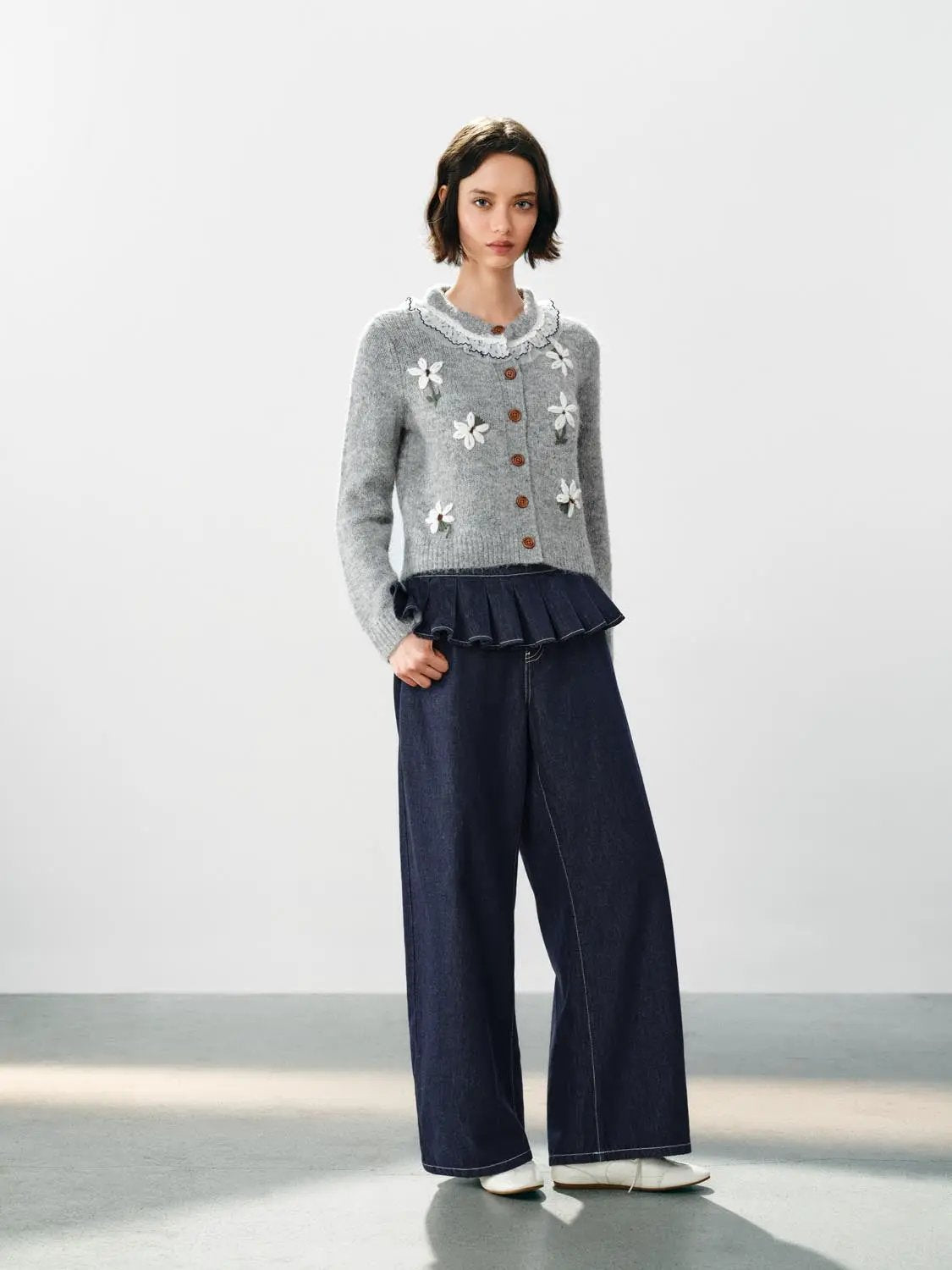 Floral-embroidered grey knitted cardigan with ruffle collar and wooden buttons; 2-piece outfit: denim wide-leg pants.