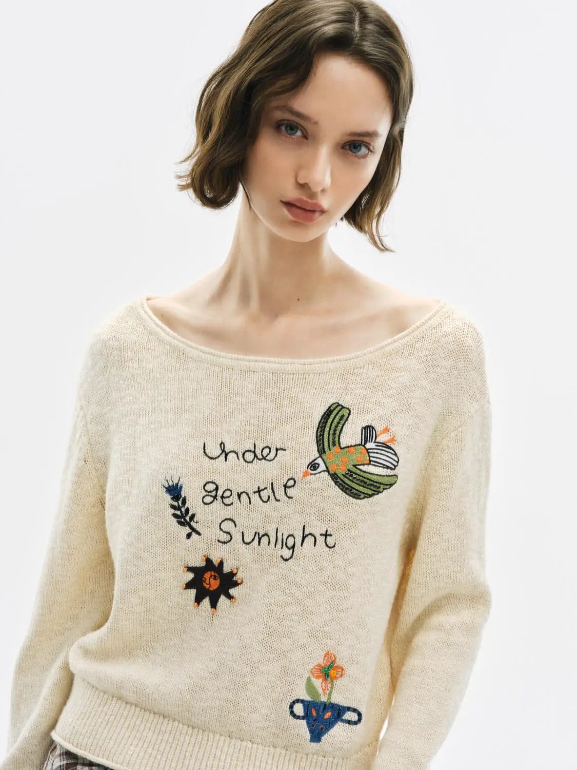 Text embroidered boat neck long sleeve cotton sweater in cream with colorful embroidery.