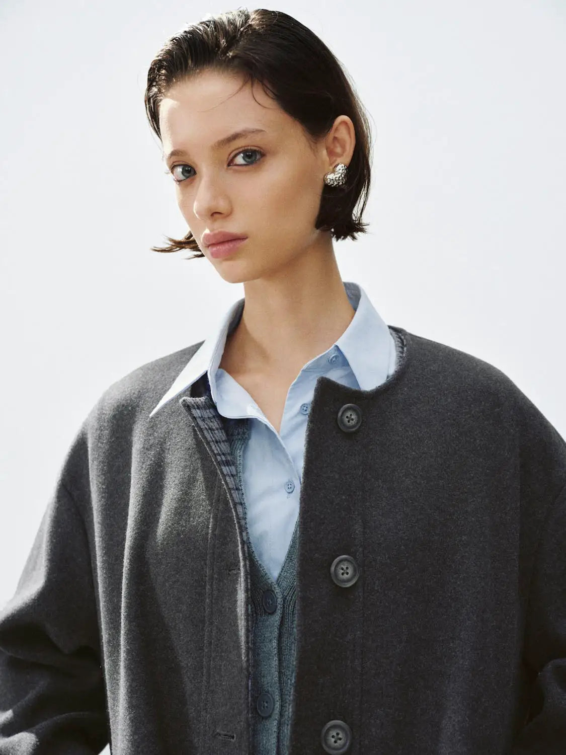 Coat by Urban Revivo Fashion; dark grey wool over a light blue shirt and layered cardigan, front view.