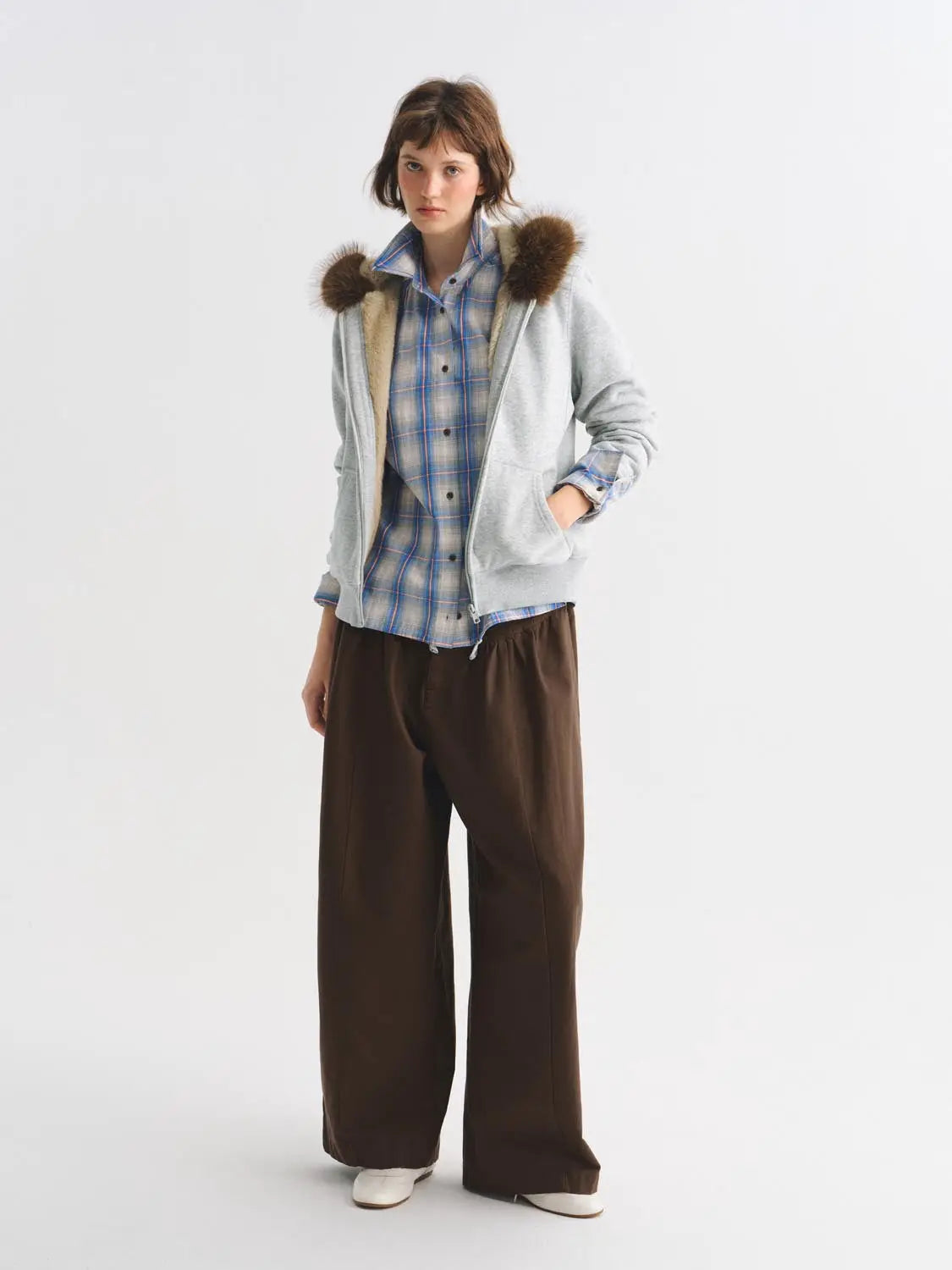 Other jacket, light gray zip hoodie with fur-trimmed hood, worn over blue plaid shirt and brown wide-leg pants.