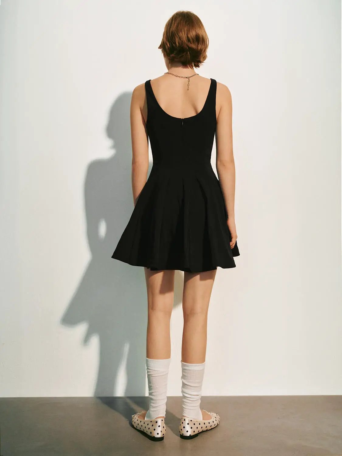 A-line sleeveless square-neck black dress with a pleated skirt