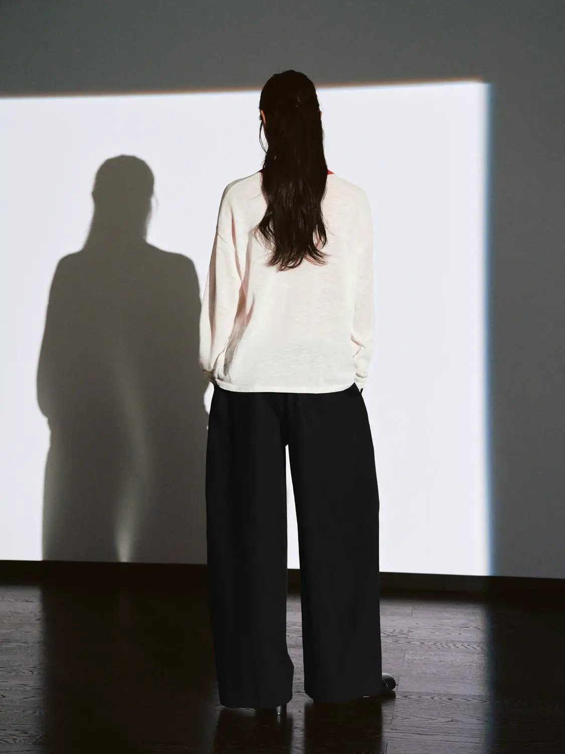 Knit T-Shirt in ivory worn from the back, paired with black wide-leg pants