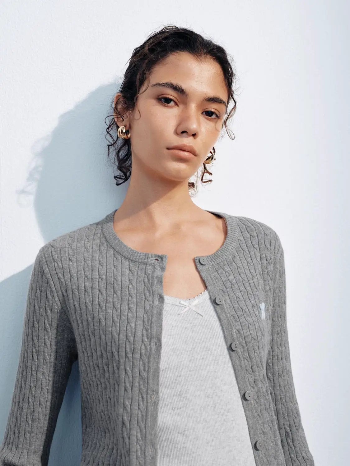 Knit jacket, gray cable-knit cardigan with long sleeves, front buttons and ribbed edges worn by a model