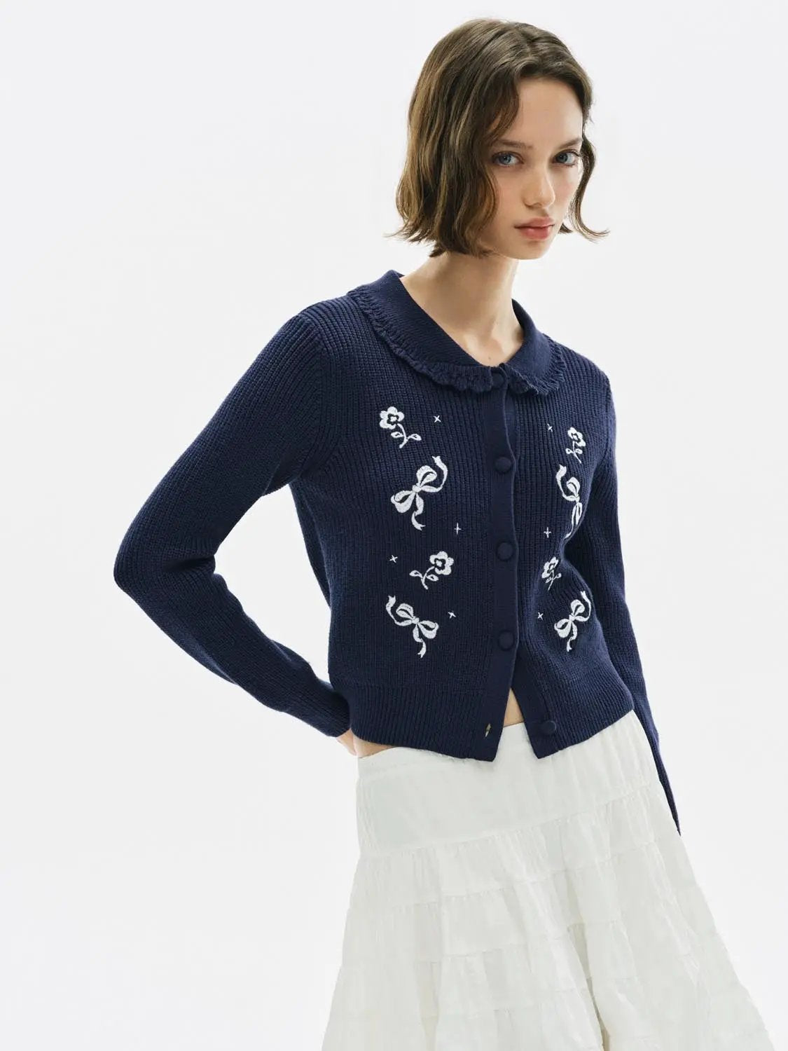 Knitwear jacket in navy knit with white floral embroidery, button-front cardigan with frill collar.