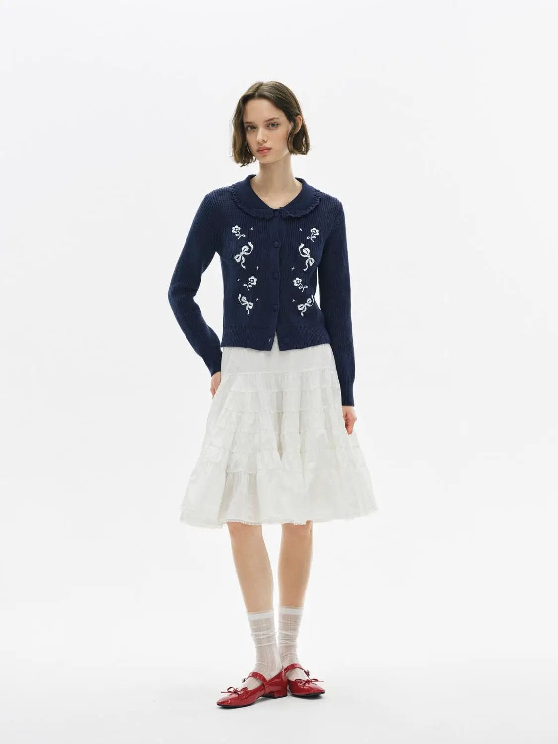 Knitwear Jacket navy cardigan with white floral embroidery by Urban Revivo Fashion, paired with a white tiered skirt.