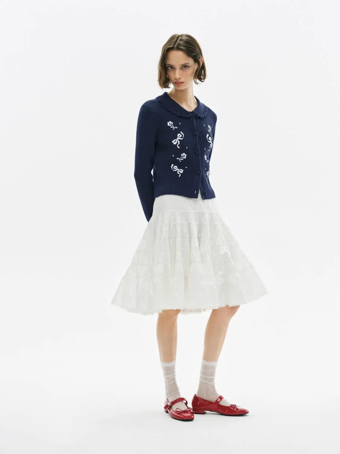 Knitwear cardigan in navy with white embroidered flowers, paired with a white tiered skirt.