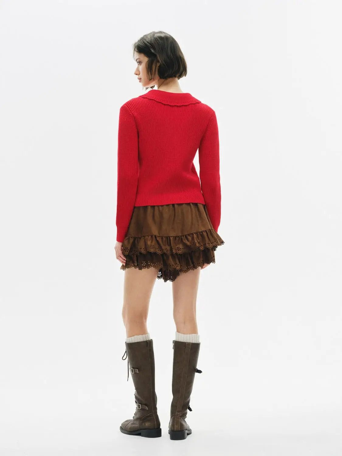 Knitted cardigan in red worn by model with a brown tiered skirt and knee-high boots.