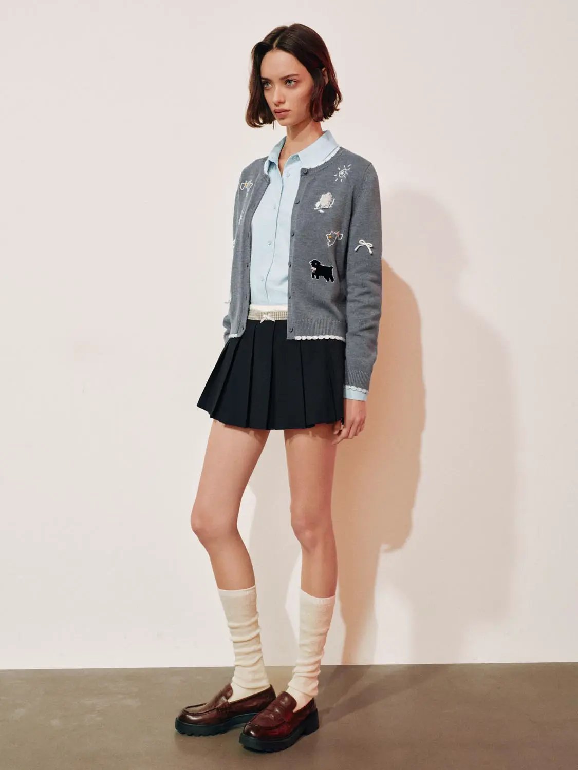 Graphic long sleeve ribbed knit cardigan, grey, by Urban Revivo Fashion; styled with blue shirt and black pleated skirt.