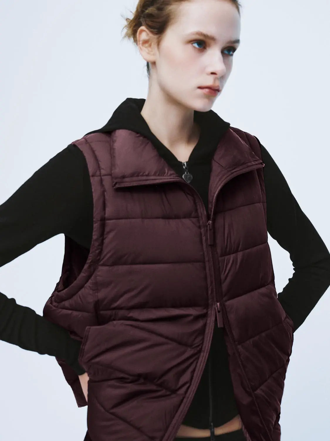 Padded jacket in burgundy quilted fabric with front zipper over a black hoodie