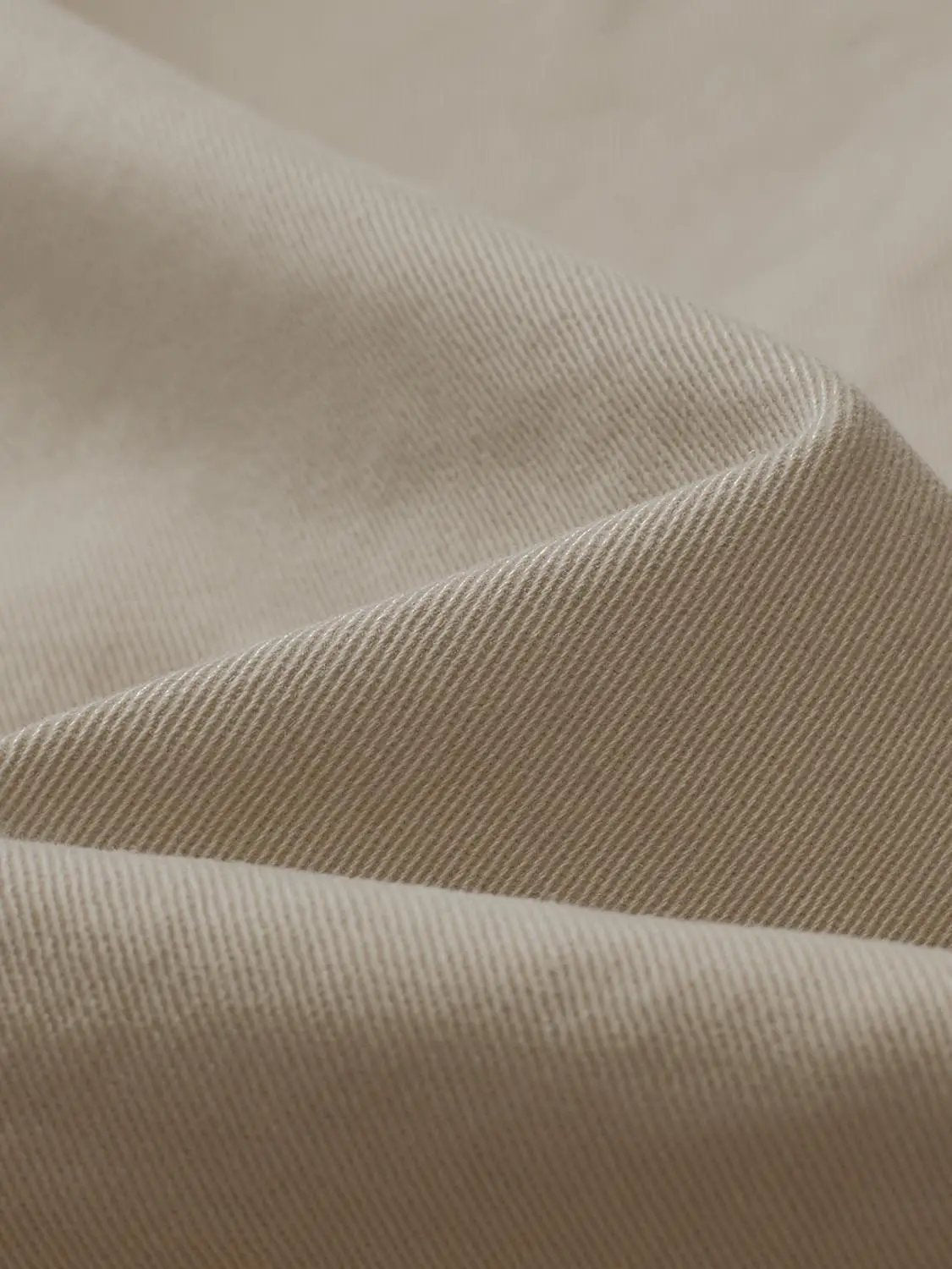 Overhead shirt beige fabric close-up with soft woven texture.