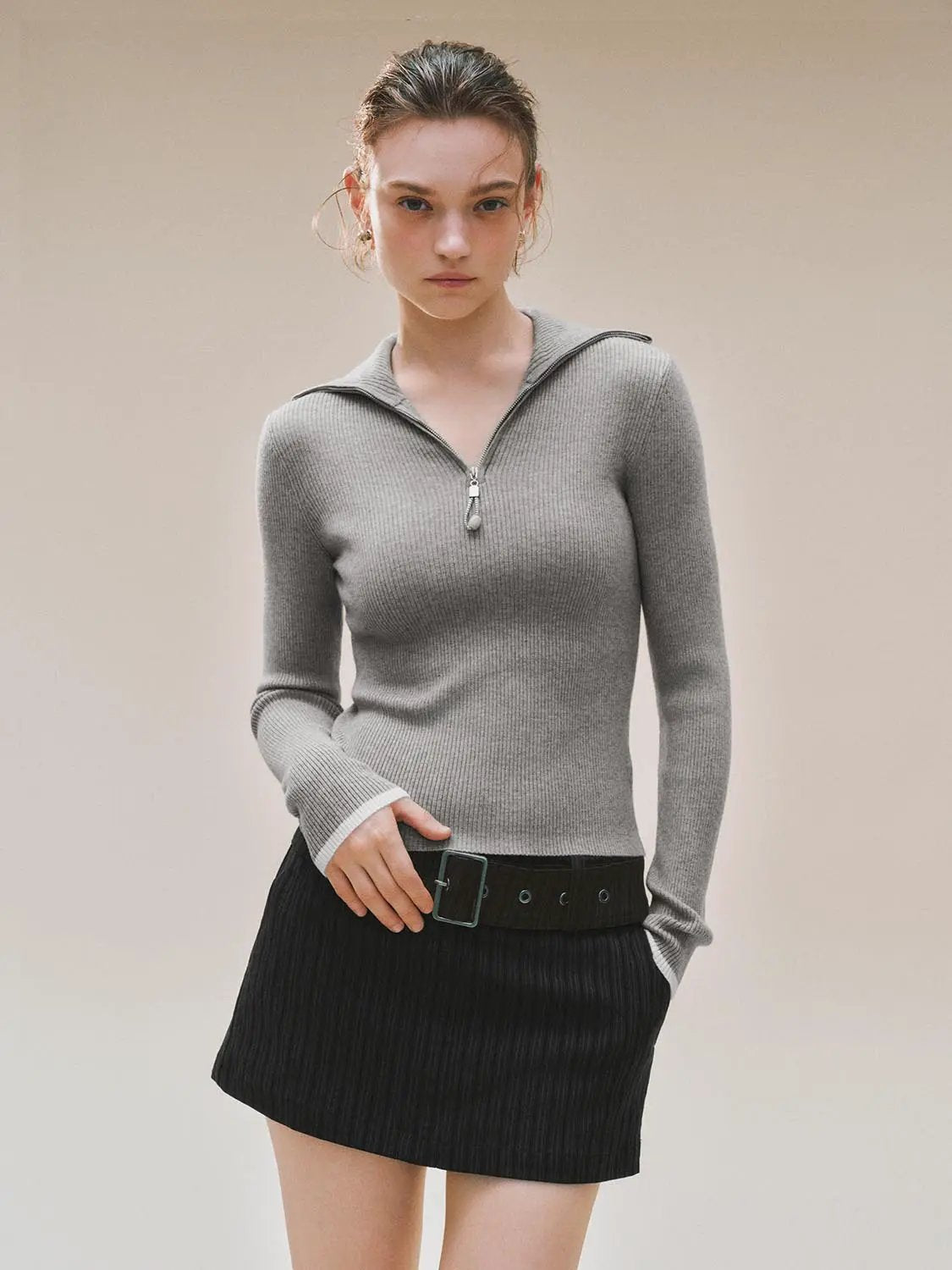 Gray ribbed knitted T-shirt with zip neck; long sleeves, shown with a black belted skirt