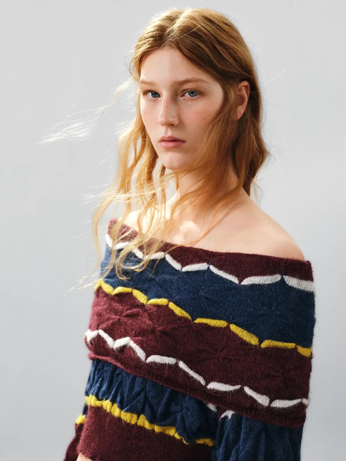 Cropped striped textured long-sleeve knit sweater in burgundy and navy with white and mustard stripes, on model.
