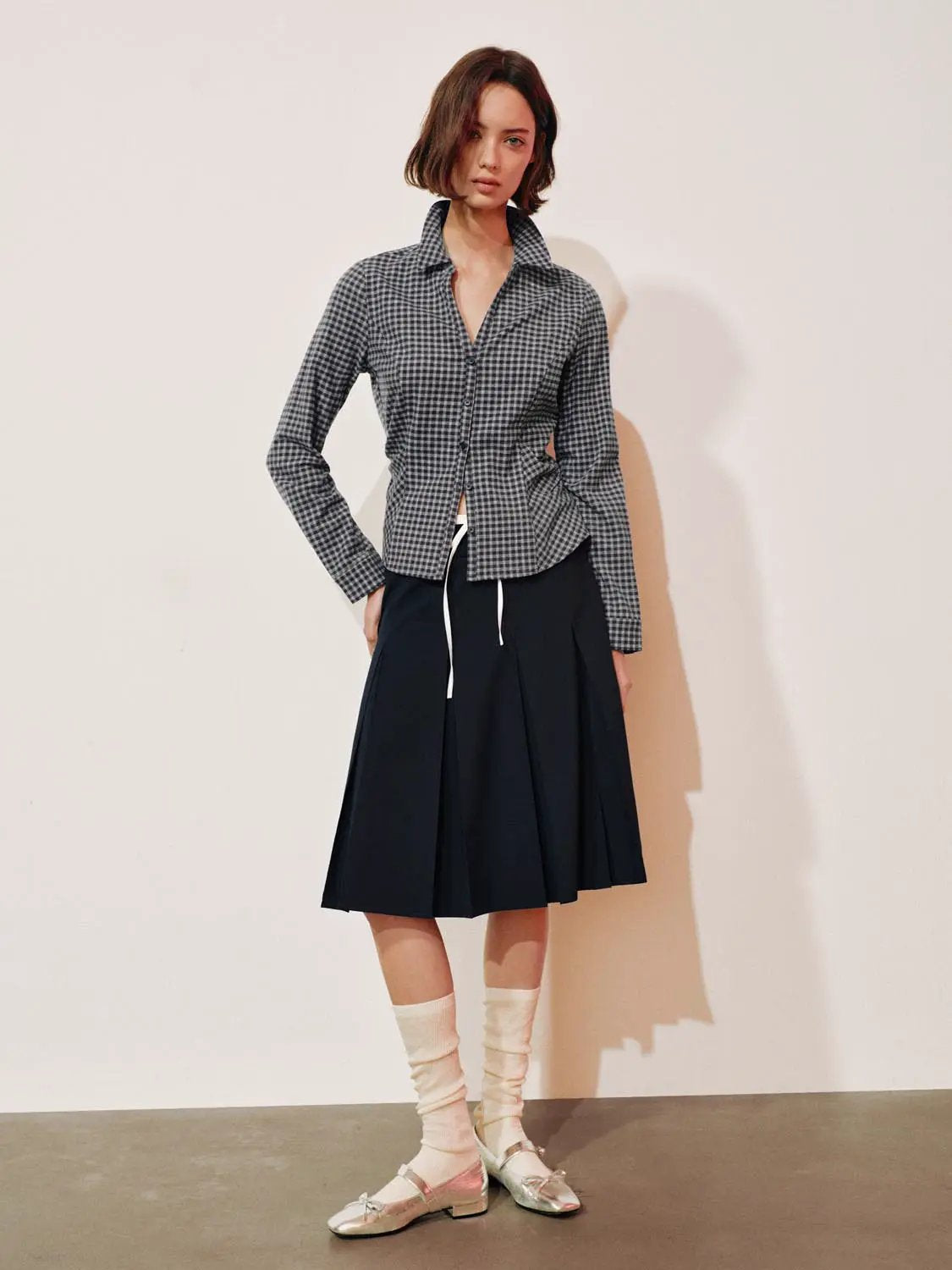 Button-front checkered shirt in gray and black, paired with a navy pleated skirt
