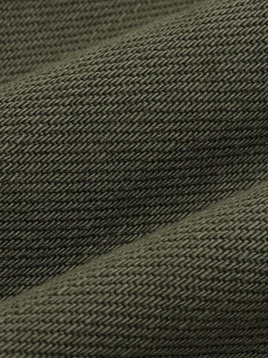 Olive cotton denim shorts fabric close-up with diagonal twill texture