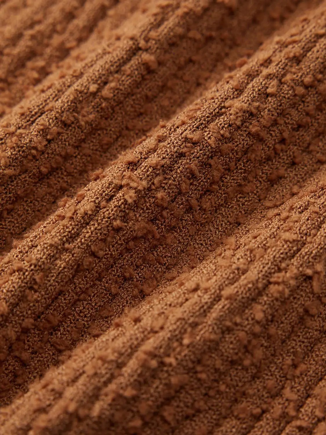 Knitted vest fabric in warm brown with close-up textured yarn.