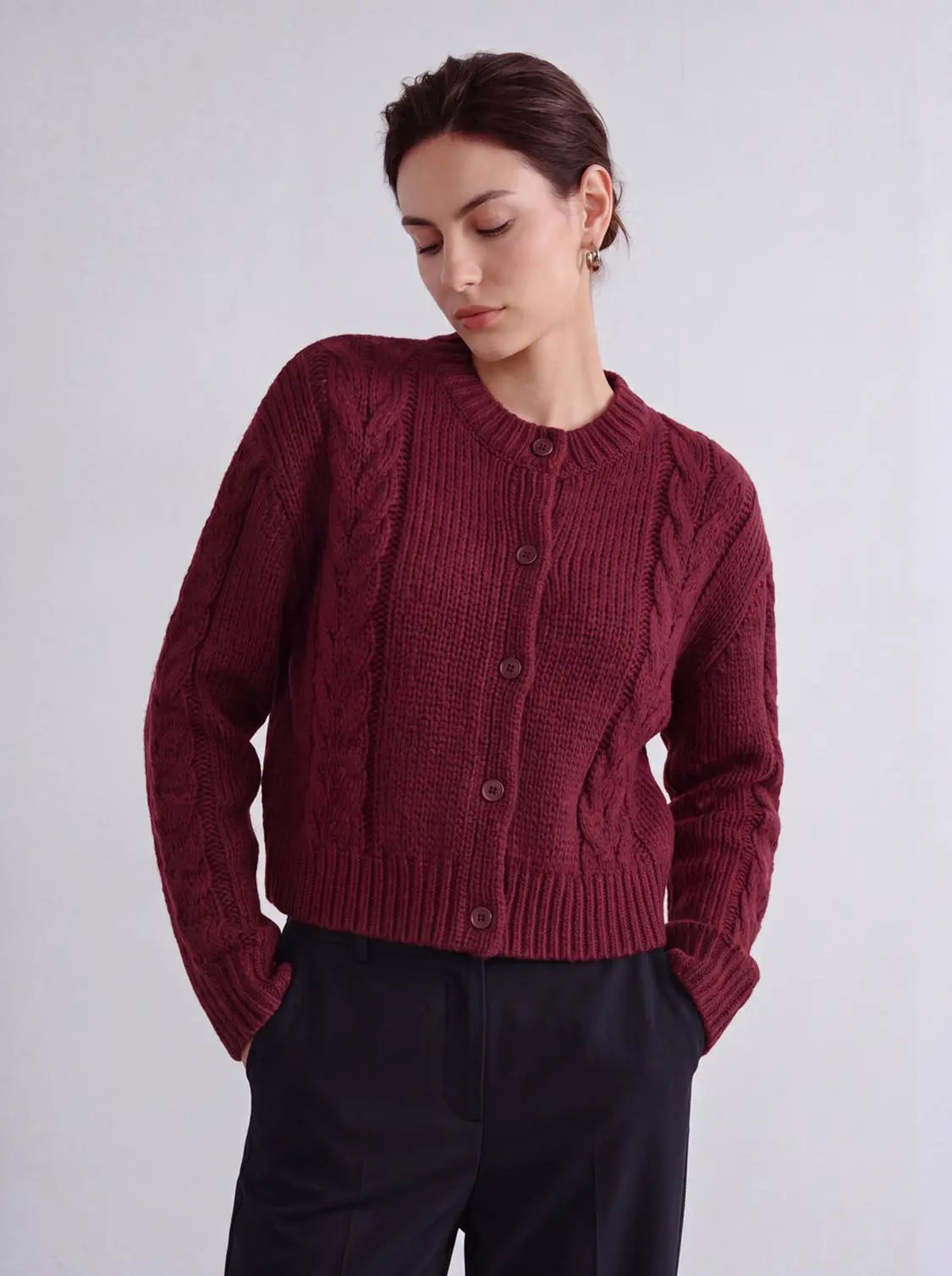 Button-up burgundy chunky cable-knit cardigan with front buttons and ribbed hem.