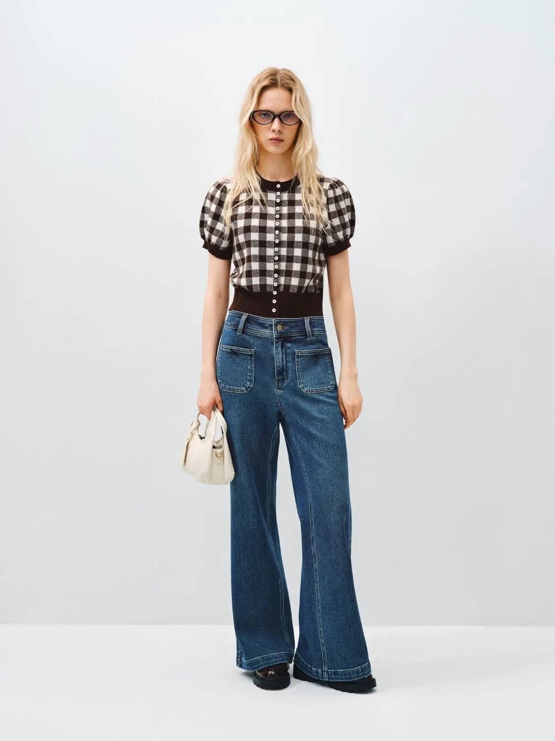 Knitted cardigan with black-and-white check pattern, puff sleeves, button front, worn with wide-leg jeans.